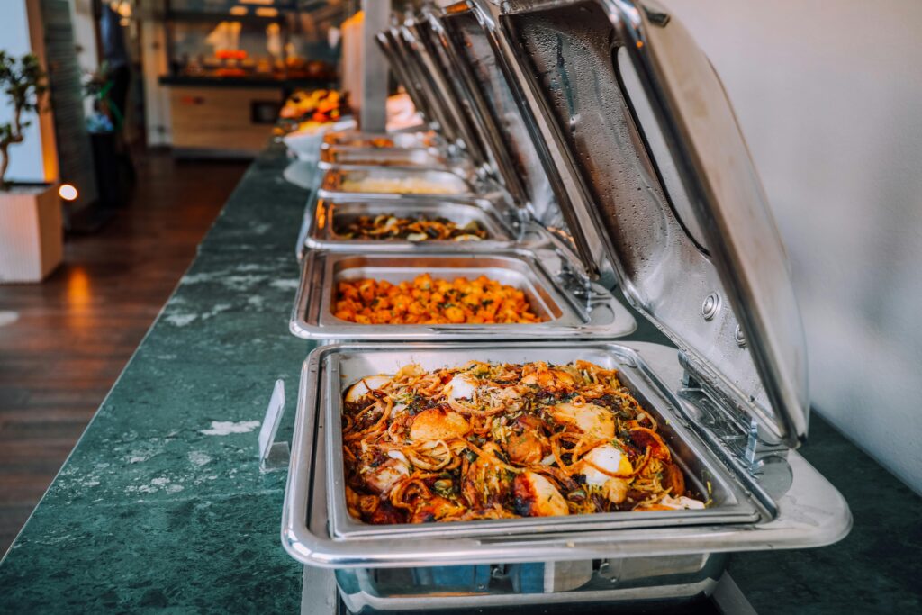 An elegant buffet setup featuring various delicious dishes in stainless steel chafing dishes, perfect for events.